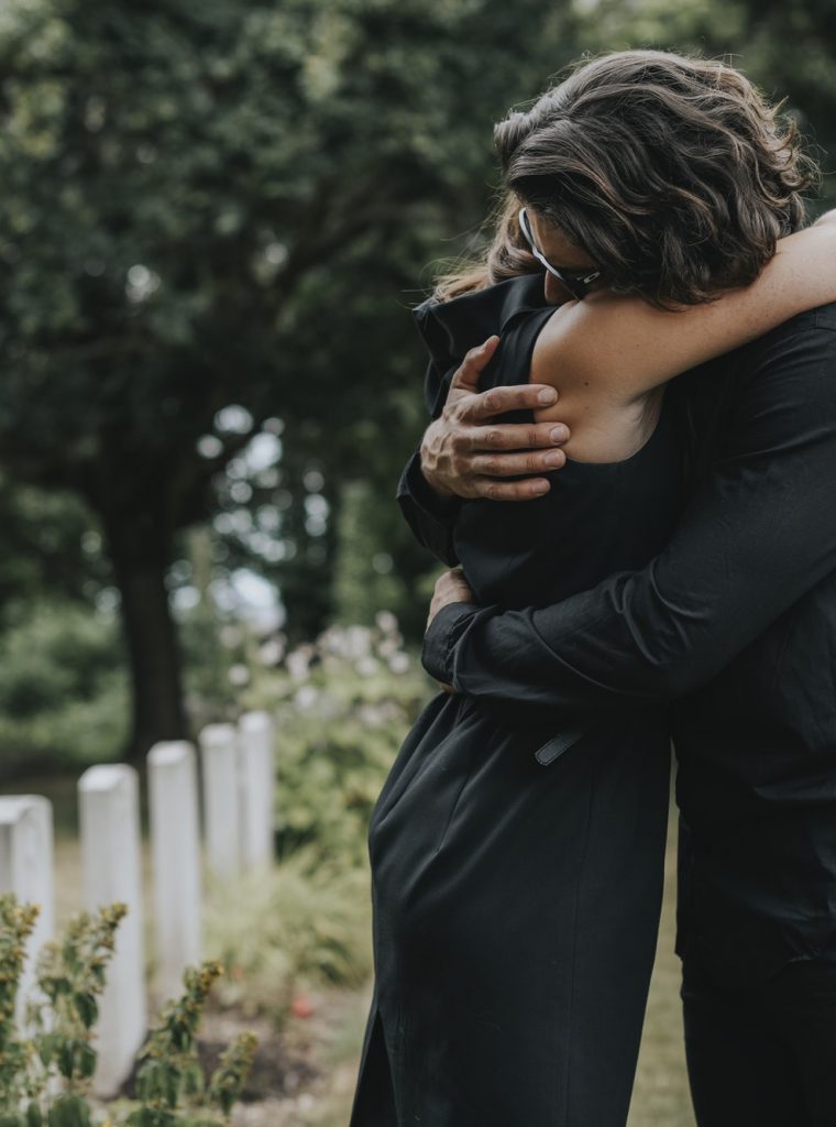 husband-trying-to-comfort-his-wife-at-a-graveyard-pfv36eiqbfltn8sfs07m4nqjx9h8mniusixa8oox6o